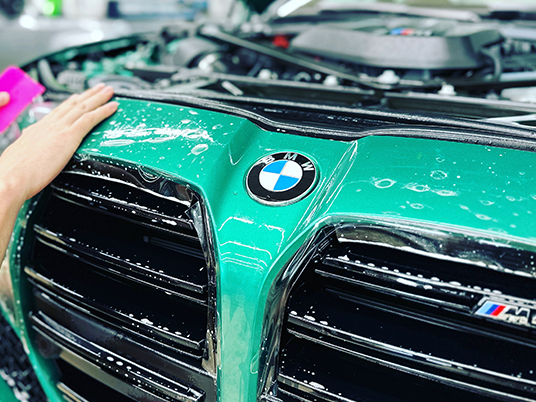 Appling XPEL PPF paint protection film to green BMW