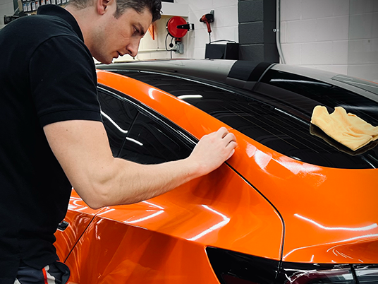 Applying XPEL Fusion ceramic coating to an orange car